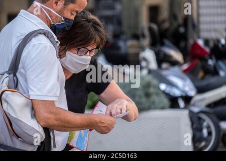 Barcelone, Espagne. 30 juin 2020. Un couple touristique portant des masques faciaux est vu en consultant une carte de la ville de Barcelone pendant leur visite.Barcelone attend l'arrivée des touristes cependant malgré la réouverture des frontières, le centre-ville en particulier le secteur de divertissement comme les bars et les restaurants affichent toujours des signes de crise Covid-19. Crédit : SOPA Images Limited/Alamy Live News Banque D'Images