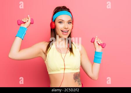 bonne sportive dans l'entraînement de casque avec haltères sur fond rose Banque D'Images