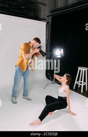 Vue latérale du photographe travaillant avec un magnifique modèle au sol dans un studio photo Banque D'Images