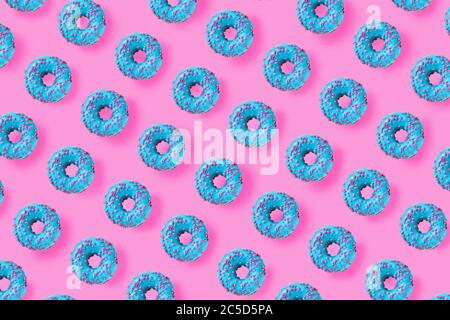 Motif de beignets bleus sur fond rose vif. Pose à plat Banque D'Images