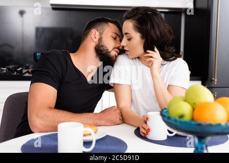 attention sélective de la jeune femme et petit ami beau près des tasses et petit déjeuner savoureux sur la table Banque D'Images