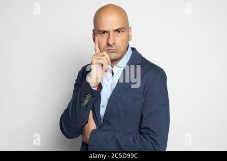 Homme chauve sérieux en blouson bleu pensant. Isolé sur fond gris Banque D'Images