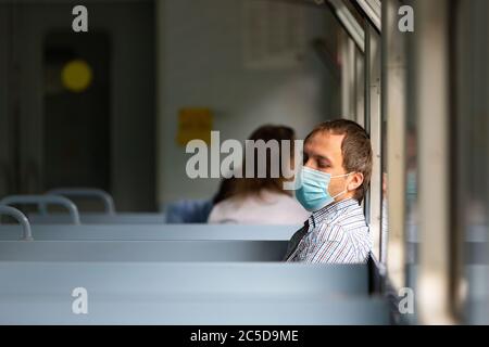 L'homme triste porte un masque protecteur dans le train pour protéger le système respiratoire contre l'infection à coronavirus, Covid-19. Mesure préventive. Nouvelle normale. Banque D'Images