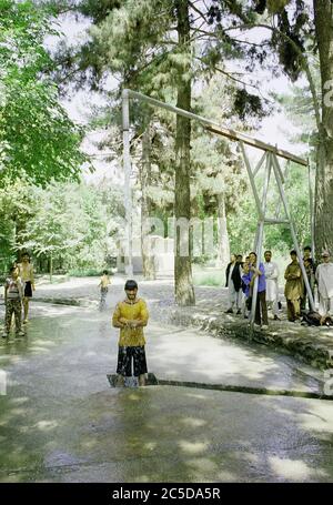 Le jeune homme se rafraîchit sous la conduite d'eau dans le parc pendant la chaleur estivale à Kaboul 2009 Banque D'Images