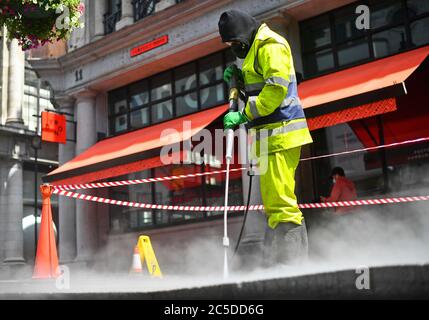 Un travailleur nettoie les rues autour de Haymarket à Londres avant la levée de nouvelles restrictions de verrouillage en Angleterre samedi. Banque D'Images