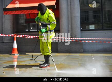 Un travailleur nettoie les rues autour de Haymarket à Londres avant la levée de nouvelles restrictions de verrouillage en Angleterre samedi. Banque D'Images