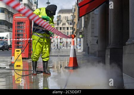 Un travailleur nettoie les rues autour de Haymarket à Londres avant la levée de nouvelles restrictions de verrouillage en Angleterre samedi. Banque D'Images