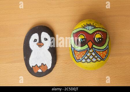 pingouin et hibou peints sur des galets de plage dans le cadre d'un projet d'art scolaire Banque D'Images