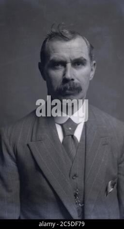 Vers 1920, portrait d'un gentleman anglais avec une moustache épaisse, portant un costume trois pièces à épingle strip avec un col boutonné ou un tour de cou sur la chemise et une épingle à cravate et une chaîne et une montre de poche attachées au gilet, Banque D'Images