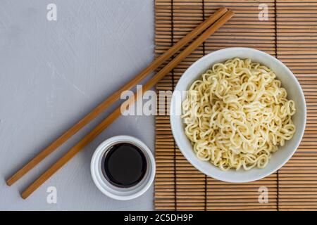 Bol de nouilles cuites simples avec des baguettes et petit bol de sauce soja - photo avec espace texte Banque D'Images