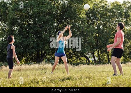 Jeune famille s'amusant à jouer avec une balle dans un jardin ou un parc comme un jeune couple et leur fils s'exercent ensemble dans un concept de style de vie actif Banque D'Images