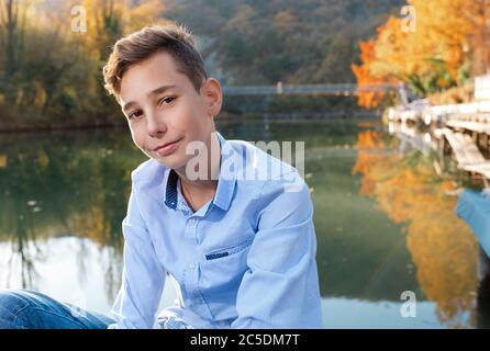 Portrait d'un adolescent souriant posant dans le parc sur le fond de la rivière et des arbres Banque D'Images