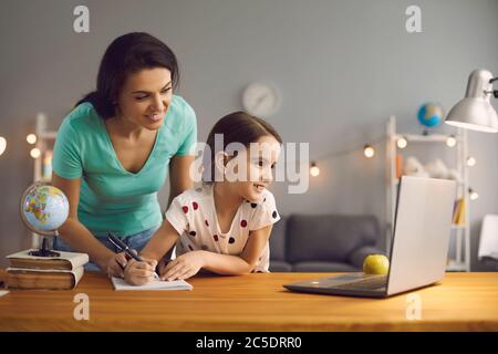 Mère et fille regardant la leçon professeur de conférence assis à distance à la table à la maison. Banque D'Images