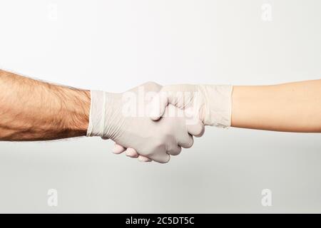 Homme et femme se serrant la main dans des gants médicaux. Banque D'Images