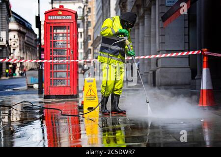 Un travailleur nettoie les rues autour de Haymarket à Londres avant la levée de nouvelles restrictions de verrouillage en Angleterre samedi. Banque D'Images