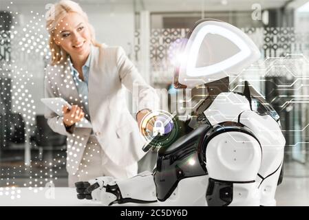 femme d'affaires souriante qui utilise le robot tout en tenant une tablette numérique, illustration de la cyber-sécurité Banque D'Images