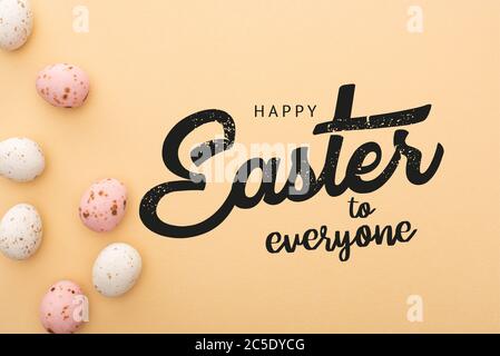 Vue de dessus des œufs de caille colorés sur fond beige avec Joyeux Pâques à tous les dessins Banque D'Images