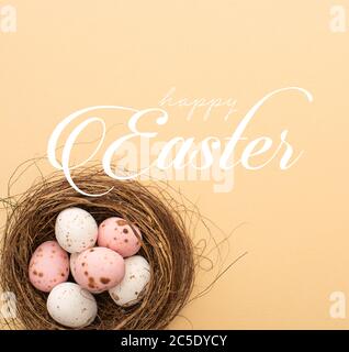 Vue de dessus des œufs de caille rose et blanc sur fond beige avec illustration joyeuses Pâques Banque D'Images