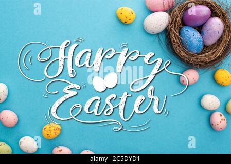 Vue de dessus de poulet coloré et des œufs de caille avec nid sur fond bleu avec illustration joyeuses Pâques Banque D'Images