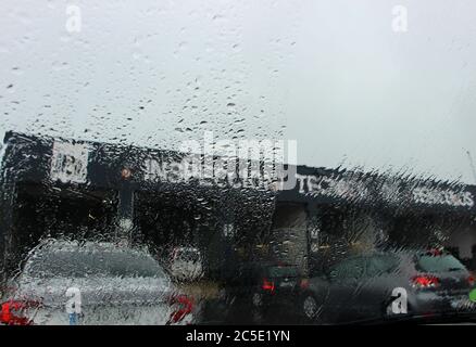 Mise en file d'attente pour une inspection de véhicule équivalente à un mot britannique Appelé un ITV en Espagne vue à travers le pare-brise obscurci par pluie battante par temps nuageux Banque D'Images