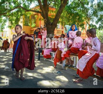 Amarapura, Mandalay, Myanmar - jeunes moines bouddhistes à l'école dans le monastère. Garçons portant un peignoir rouge foncé et filles portant un peignoir rose. Banque D'Images