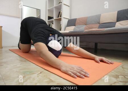 Homme asiatique faisant de l'exercice à la maison pour rester en bonne santé sur un nouveau mode de vie normal, concept d'entraînement à la maison d'intérieur, s'étendant pour la flexibilité Banque D'Images