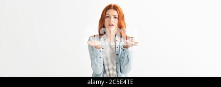 photo panoramique d'une jeune fille inquiète dans des vêtements en denim avec un geste haussement d'épaules, isolée sur blanc Banque D'Images