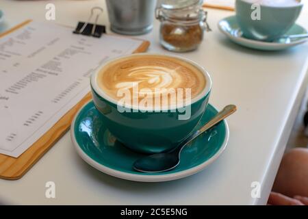 caffee latte macchiato cappuccino bleu turquoise mug dans café maison avec mousse de lait art . Banque D'Images