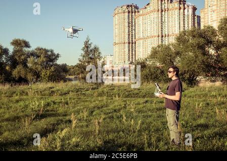 Homme utilisant un drone quad copter avec caméra numérique embarquée dans le parc de la ville Banque D'Images