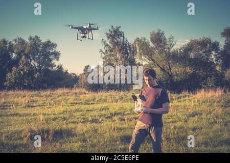 Homme utilisant un drone quad copter avec caméra numérique embarquée dans un parc Banque D'Images