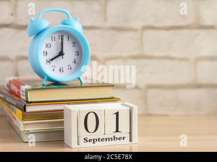 Retour à l'école, le 1er septembre sur le calendrier. Réveil et une pile de manuels sur la table Banque D'Images