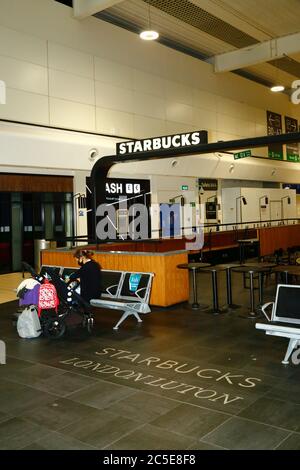 2 juillet 2020, aéroport de Luton, Royaume-Uni : un passager portant un masque facial se trouve à côté d'un café Starbucks fermé dans les salons de départ de l'aéroport de Luton. Le nombre de vols entre le Royaume-Uni et certains pays européens commence à augmenter et les gouvernements devraient bientôt annoncer des ponts aériens entre les pays pour faciliter les voyages et le tourisme. L'impact économique du virus sur le commerce de détail et d'autres secteurs sera sévère, et de nombreuses entreprises seront encore fermées Banque D'Images