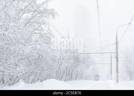 Le tramway longe la rue pendant la tempête de neige en hiver à Moscou, en Russie. Vue panoramique sur une rue enneigée de la ville. Hiver Moscou fond. Froid et neige Banque D'Images