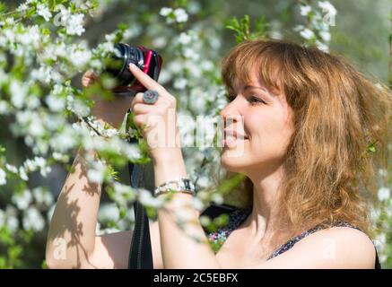 Une jeune femme photographie la fleur de cerisier le jour du printemps Banque D'Images