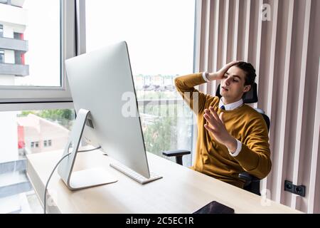 Homme d'affaires frustré assis à la réception avec la main dans le bureau Banque D'Images