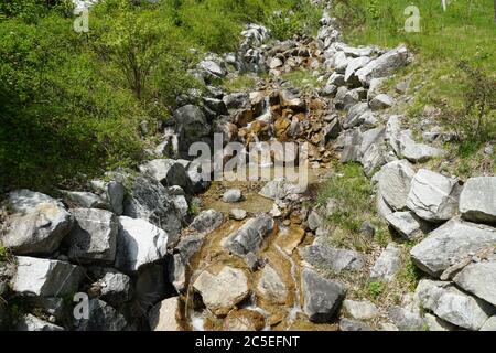 Bassin fluvial bordé de grandes pierres dans la région alpine d'Engelberg, canton d'Obwalden, au début du printemps, avec un faible niveau d'eau. Banque D'Images