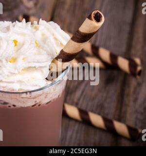 Chocolat chaud avec garniture à la crème fouettée, en verre avec galette roulée. Traitement des effets vintage Banque D'Images