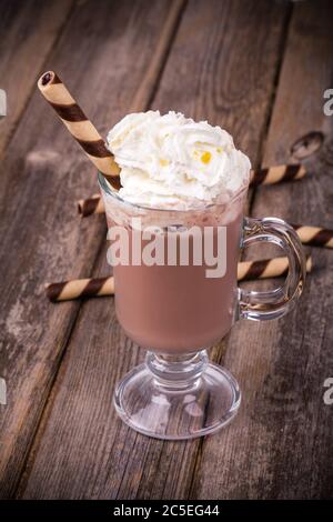 Chocolat chaud avec garniture à la crème fouettée, en verre avec galette roulée. Traitement des effets vintage Banque D'Images