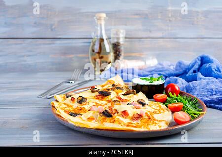 Crêpes délicieuses avec champignons, jambon et fromage, arugula, tomates et crème sure sur fond de bois Banque D'Images