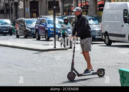 Londres, Royaume-Uni. 2 juillet 2020. Un homme fait un scooter électrique personnel (e-scooter) dans Regent Street. Le ministère des Transports permettra à la location de scooters électroniques de devenir légale sur les routes en Grande-Bretagne à partir du 4 juillet, pour une période d'essai de 12 mois, afin d'essayer d'alléger la pression sur les transports publics pendant la pandémie du coronavirus. Les conducteurs ont besoin d'un permis de conduire, de motocyclette ou de cyclomoteur complet ou provisoire pour utiliser les véhicules, et ils doivent être âgés de 16 ans ou plus. Actuellement, il est offense de conduire des e-trottinettes personnelles sur une route publique britannique, une piste cyclable ou une chaussée. Credit: Stephen Chung / Alay Live News Banque D'Images