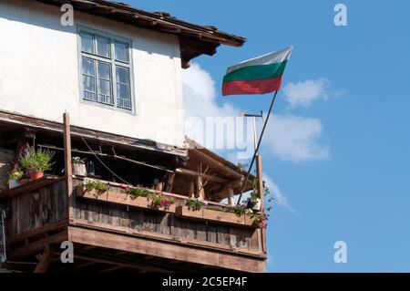 Le drapeau bulgare vole sur le balcon d'une maison traditionnelle et authentique du XIXe siècle de style historique Revival architecture à Kovachevitsa, Bulgarie Banque D'Images