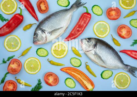 Poisson et légumes Dorado : concombre, tomate, poivre, citron sur fond bleu. Texture de fond pour la cuisine Banque D'Images