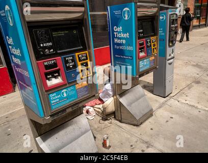 Un homme sans domicile dort contre les kiosques de billets d'autobus SBS à Chelsea, à New York, pendant la pandémie COVID-19, le mardi 30 juin 2020. (© Richard B. Levine) Banque D'Images