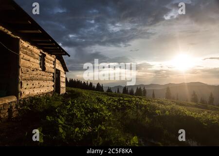 Des rayons du soleil en soirée brillent sur une maison en bois dans les montagnes. Carpates, MarMarmaris, Maramures, Ukraine Banque D'Images