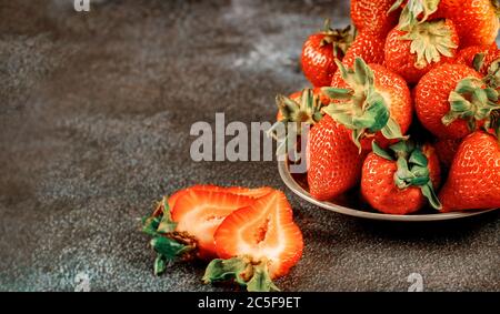 Fraises saines de saison dans une assiette sur fond sombre. Gros plan. Banque D'Images