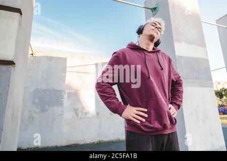 Sportsman se réchauffe, fait des exercices de rotation du cou et écoute de la musique dans un casque Banque D'Images