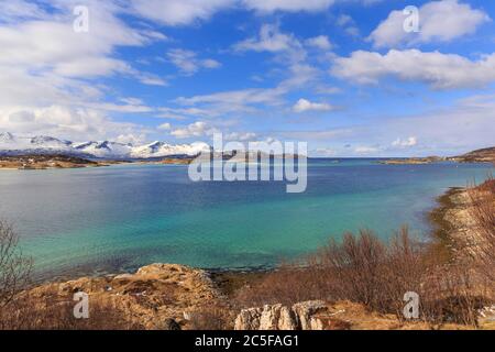 Mer turquoise, derrière les montagnes enneigées de l'île de Senja, Sommaroysund, Sommaroy, Troms, Norvège Banque D'Images