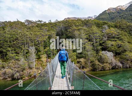 Jeune homme sur un pont suspendu au-dessus de la rivière Mavora, Mavora, Southland, South Island, Nouvelle-Zélande Banque D'Images