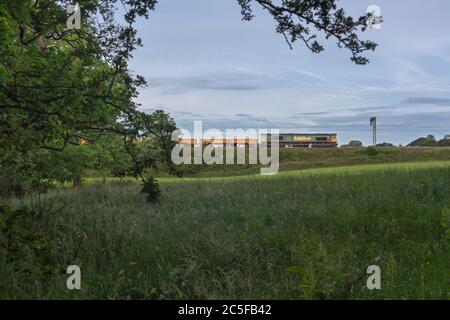 La locomotive Freightliner de classe 66 66604 dans la campagne sur la ligne principale de la côte ouest avec un train de possession de techniciens de réseau ferroviaire Banque D'Images