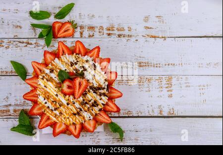 Tartelez avec de la crème fouettée et des fraises sur une surface en bois blanc. Vue de dessus. Banque D'Images